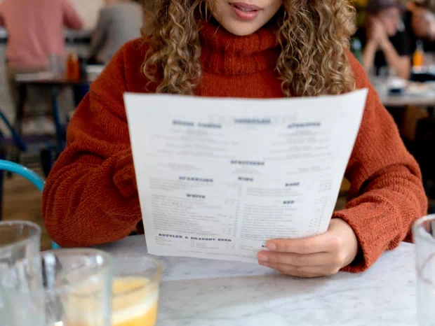 Kobieta w czerwonym swetrze czytająca menu